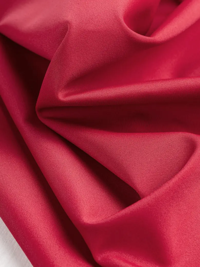 Close-up of draped, textured red fabric gathered into soft folds.