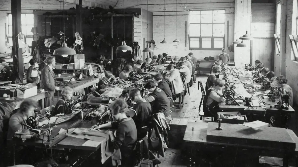 Workers diligently sewing garments at multiple sewing machines in a spacious textile workshop.