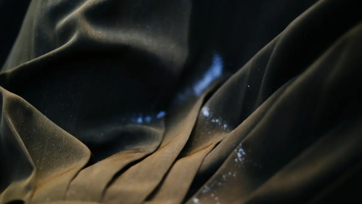 Close-up of crumpled dark fabric with visible sheen and soft pleats.